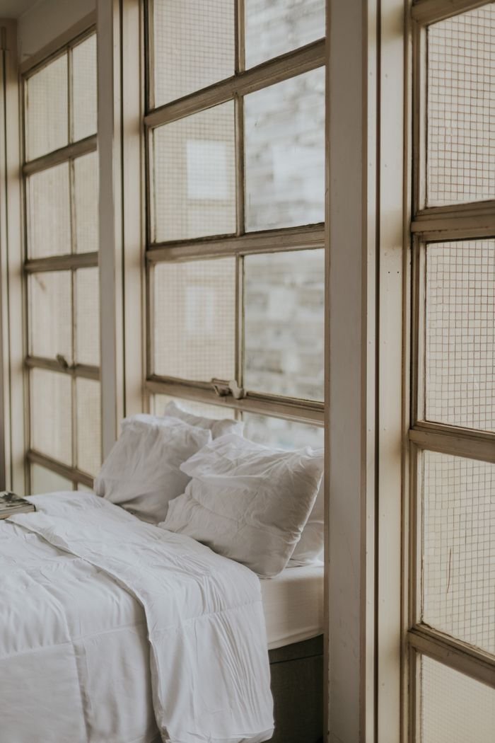 Stylish bedroom interior featuring a cozy bed and large vintage windows for natural light.